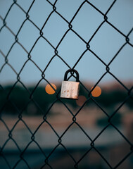 Closed padlock on metal net over sunset