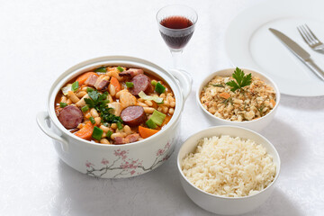 A bowl of chicken cassoulet and spicy breadcrumbs on a white table