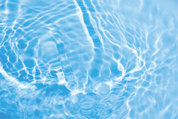 Blue water with ripples on the surface. Defocus blurred transparent blue colored clear calm water surface texture with splashes and bubbles. Water waves with shining pattern texture background.