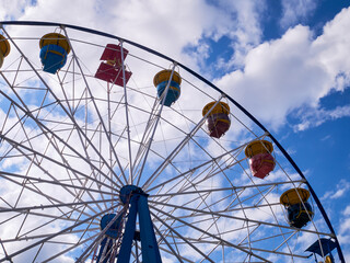 Ferris wheel in an amusement park, against the background of the sky with clouds. Rest, vacation, emotions, joy.