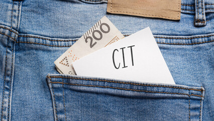White card with a handwritten inscription "CIT", put into the pocket of blue pants jeasnow, next to Polish banknotes PLN (selective focus)