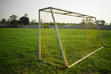 Fototapeta premium Football goal in the football field in the morning with a sunset background