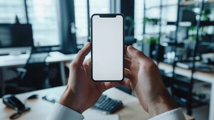 Person holding a smartphone with a blank screen in a modern office setting, ideal for showcasing mobile apps or mockups.
