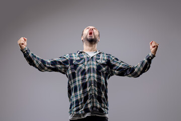 Excited bearded man raising fists and screaming in celebration