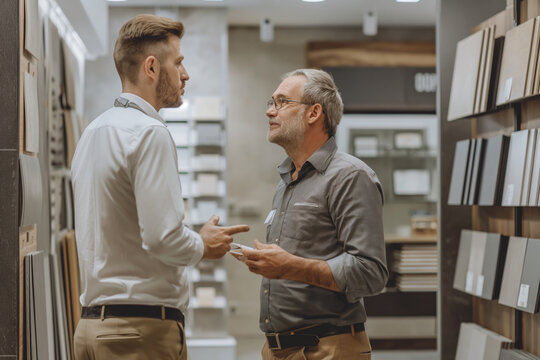 Salesman and customer in conversation at modern showroom, business interaction concept