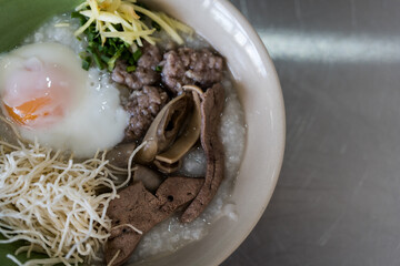 Congee with minced pork, liver, pork entrails and boiled egg in a bowl. Thai rice porridge