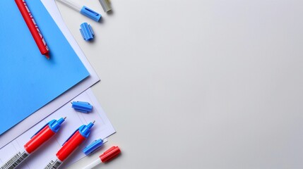 Chic and minimalist school supplies on left and right side for copy space for text on a plain background; blue sticky notes and red sharpies, planning concept