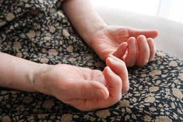 膝の上に置いた高齢女性の手