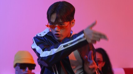 Attractive asian street dancer perform freestyle movement with neon light. Professional performer practicing moving to hip hop music with diverse friends or team at studio with led light. Regalement.