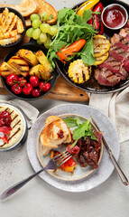 Table with grilled food. Pizza, corn, tomatoes, peppers, cooked meat. BBQ time