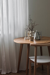 Coffee break. A cup of coffee, a metal coffee pot,  candles on a round wooden table and chair in the living room