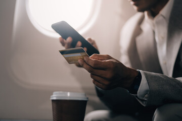 Businessman holding credit card and looking at camera near laptop in private jet