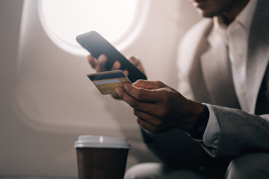 Businessman holding credit card and looking at camera near laptop in private jet
