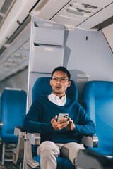 Man with dark hair is reading text message on mobile phone and speaking by phone during flying in the airplane