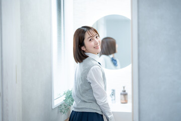 鏡の前に立ちカメラ目線で笑顔の女子高生
