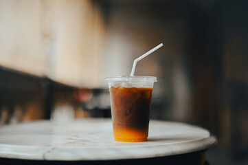 Plastic cup with clear lid and straw Contains iced tea or iced coffee drinks. The drink has a gradient from a dark brown at the top to a lighter, more translucent color at the bottom.