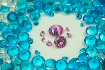 A group of Pink diamonds arranged in the middle of blue diamonds in a white background.Diamonds are highly valued as expensive pieces of jewelry..The sparkling light of the diamonds is beautiful..
