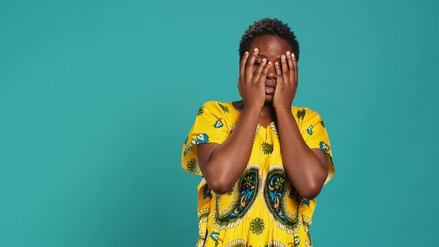 Horrified young woman covering her eyes to avoid seeing something, feeling squeamish and appalled about a thing in studio. Being disgusted and shocked in ethnic clothing. Camera A.