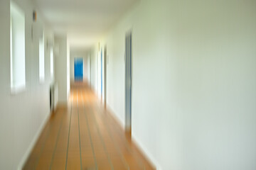 Long, hallway and window with motion blur in interior for walkway, horizontal and door at end for enter to classroom or room. Hospital, school and empty corridor with architecture, narrow and passage