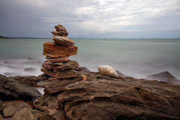 The rocks are arranged on a large rock by the seashore, with a white rock next to it