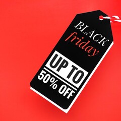 A black sale tag on a red background with the words Black Friday up to  50% off, signaling special discounts, deals, prices or promotions