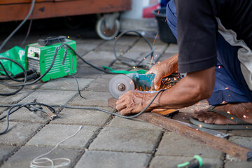 Worker using angle grinder to cut metal
