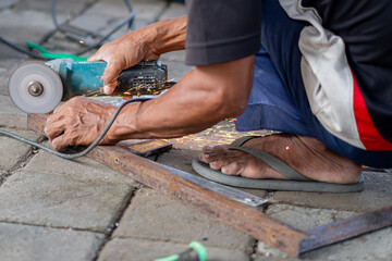 Worker using angle grinder to cut metal