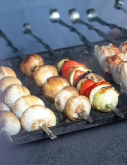 Mushrooms on skewers are fried over coals on the grill