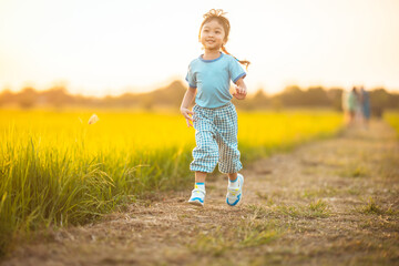 baby girl with happy time on freedom in emotional in outdoor by run play on grasses floor in rice fields blue dress