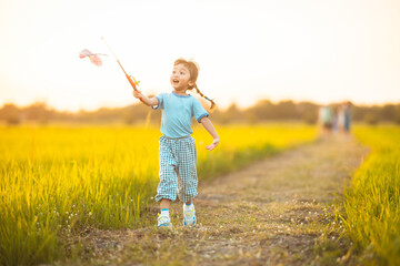 baby girl with happy time on freedom in emotional in outdoor by run play kite on grasses floor in rice fields blue dress
