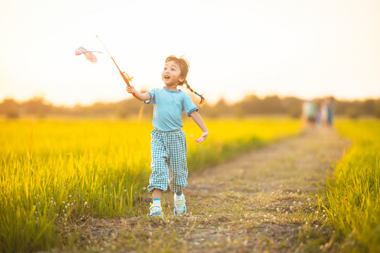 baby girl with happy time on freedom in emotional in outdoor by run play kite on grasses floor in rice fields blue dress