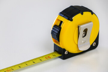 Close up of black and yellow retractable tape measure, useful tool for measuring length, width and height. Accuracy and precision concept