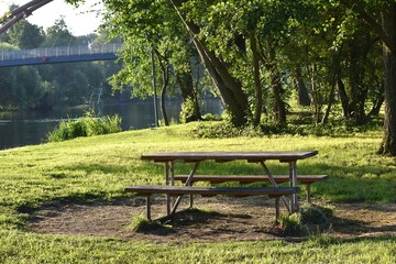 wooden bench and table in a clearing near the river bank
