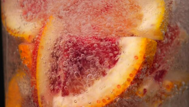 Pouring fizzy soda into glass swirling around grapefruit slices. Creating citrusy symphony of bubbles and aromas in refreshing lemonade