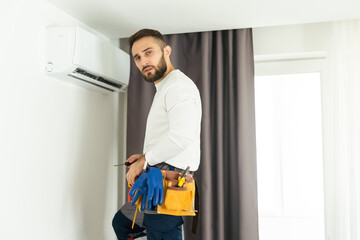 Male technician cleaning air conditioner indoors