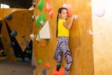 little girl climbing a rock wall indoor