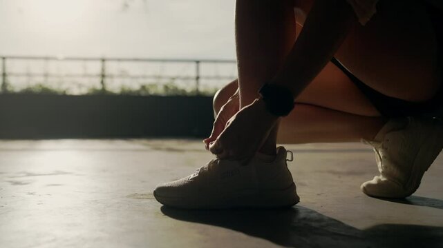 A woman is kneeling down and putting on her shoes. The image has a mood of determination and focus