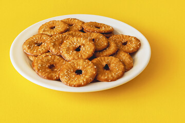 Round crackers with a hole and salt on a yellow background