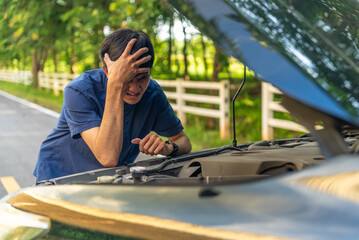 Man repairing a broken car by the road. Man having trouble with his broken car on the highway...