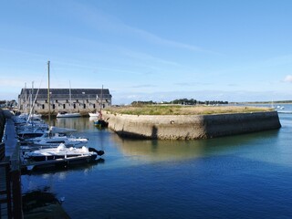 Le Croisic, France, Quay walls, jetties in the harbor entrance at low tide, sailboats are moored. In the background is a view of the former fish hall, now used as a multi-purpose cultural event hall