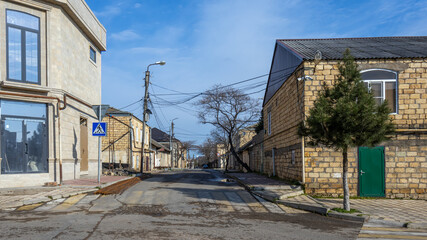 A pedestrian crossing on a street in the city of Derbent. The private sector in the city. A large number of electrical wires go from the pole to private homes.