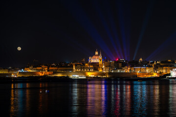 St. Pauls Cathedral Valletta, Malta at night with light show and full moon behind