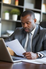 Fototapeta premium An African professional businessman reading a document in the office, sitting at the desk, working.