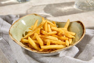 Crispy French Fries in Sunlit Bowl with Shadows on Summer Day