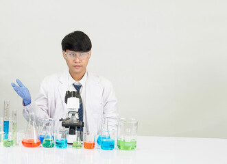 Fototapeta premium Portrait asian man student scientist Wearing a doctor gown in the lab looking hand at chemist. caused by mixing reagents in scientific research laboratories with test tubes and microscope on the table