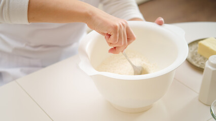 Close-up of a woman's hands kneading dough in a bowl. Process of cooking pecan pie in home kitchen for American Thanksgiving Day.