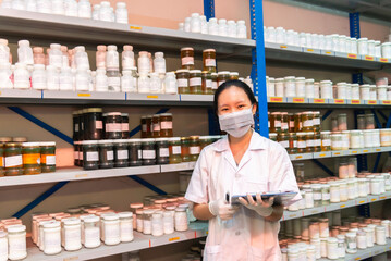 Beautiful pharmacist working and standing in a drug store and doing a stock take.