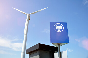 Electric car charging station sign with a wind generator in the background.