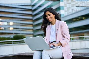 Smiling young middle eastern Israel businesswoman using online app on laptop pc. Indian or arabic...