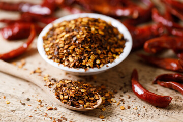 Dried red chilie and ground chilli on wooden table.